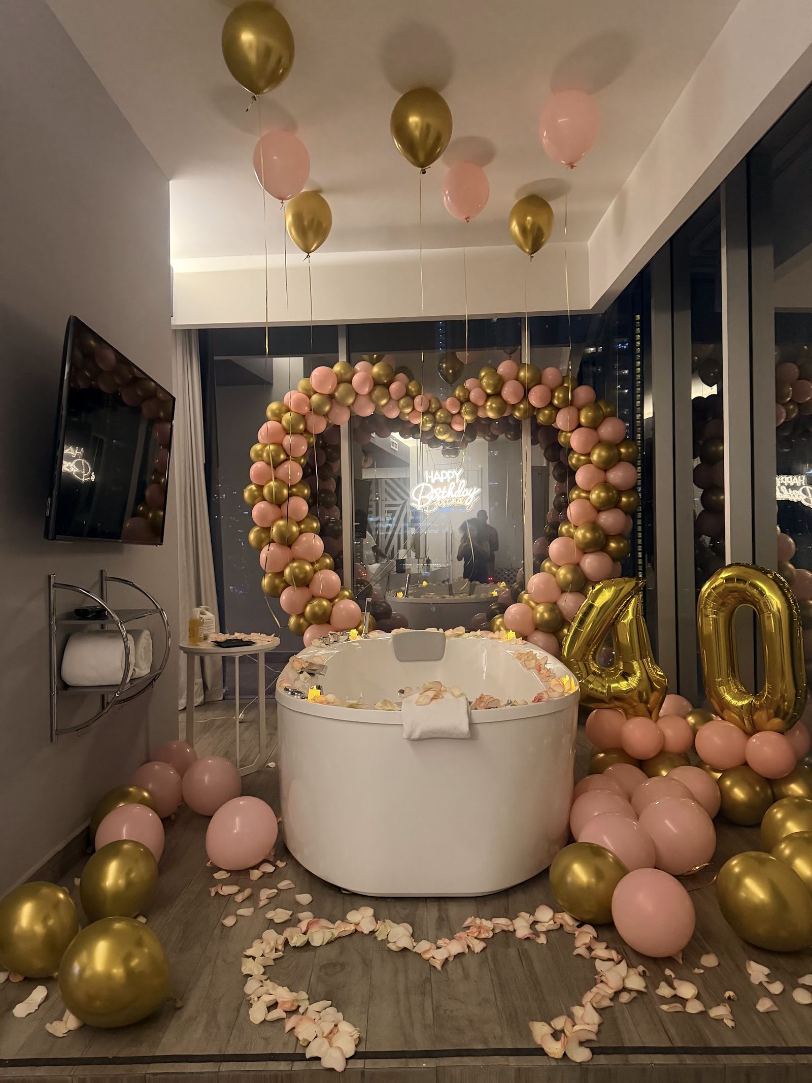 Habitación decorada con arco de globos en forma de corazón, rosado y dorado